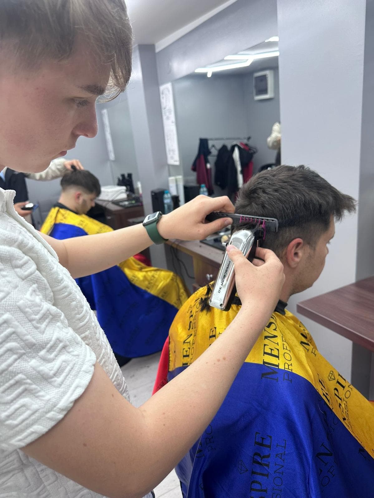 Cursant sub 18 ani la cursul de frizerie PointCut Pitești, la lucru pe model real sub supravegherea instructorului — imaginea 1