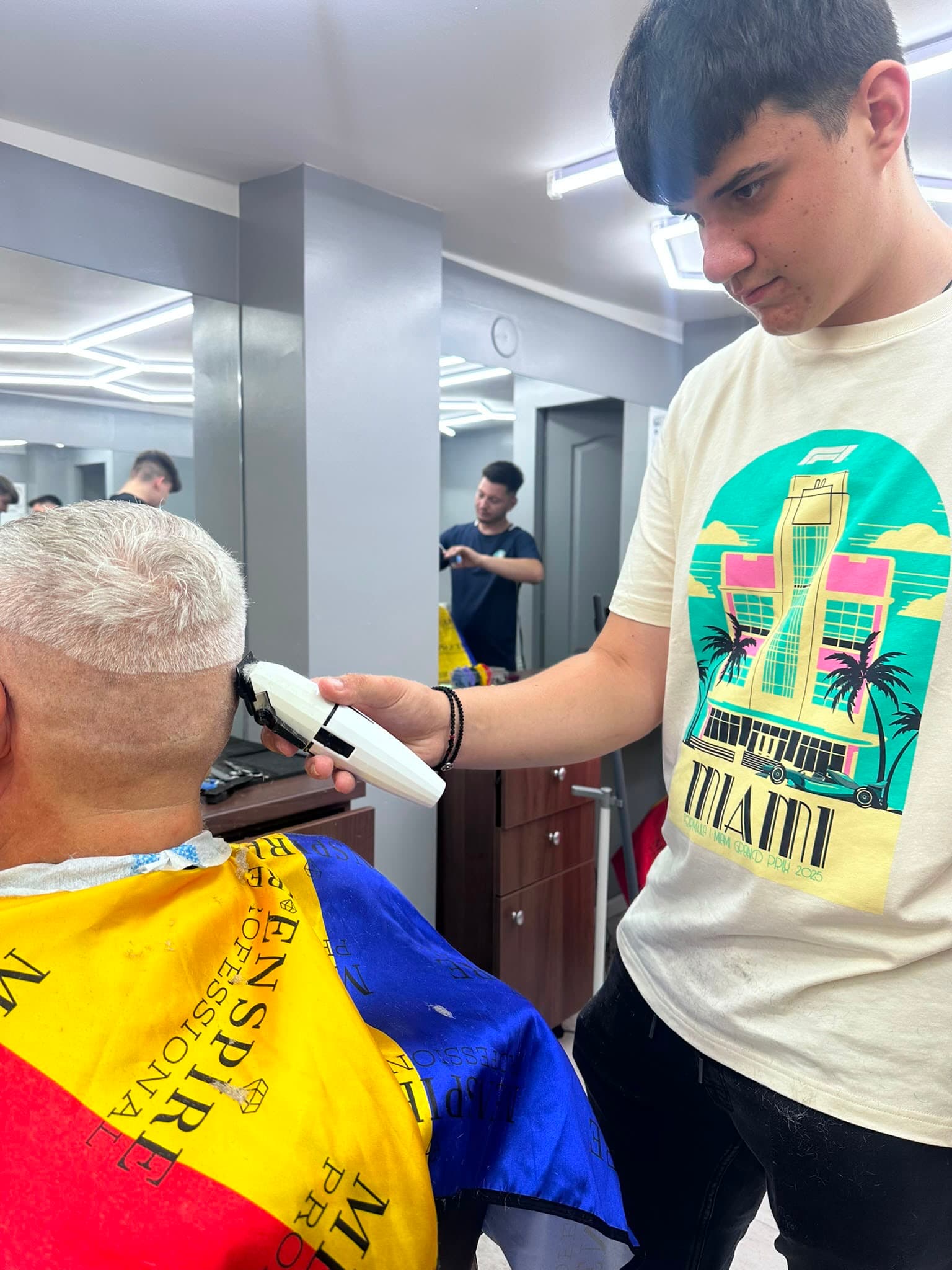Cursant sub 18 ani la cursul de frizerie PointCut Pitești, la lucru pe model real sub supravegherea instructorului — imaginea 2